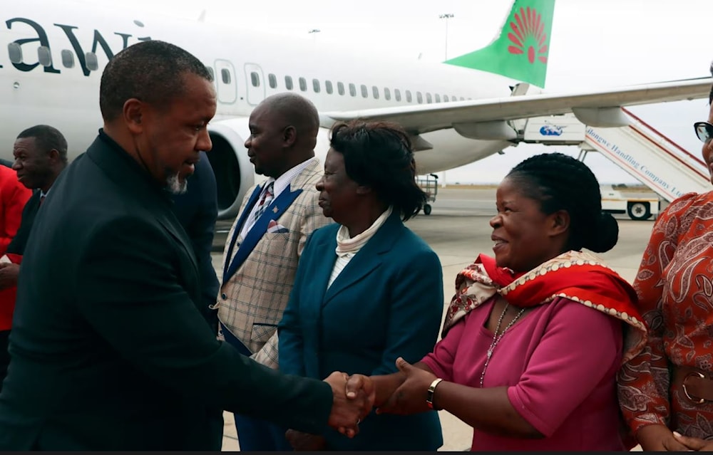 Saulos Chilima, left, greets a gathering at the airport (AP)