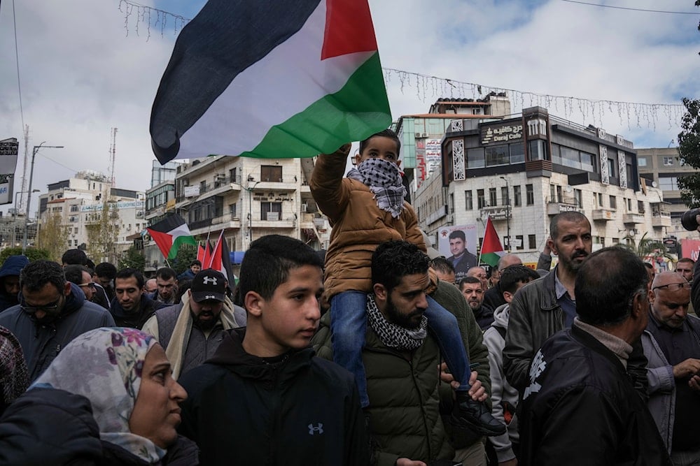 Palestinian demonstrators wave their national flag and shout slogans during a protest in the West Bank city of Ramallah, occupied Palestine, January 3, 2024 (AP)