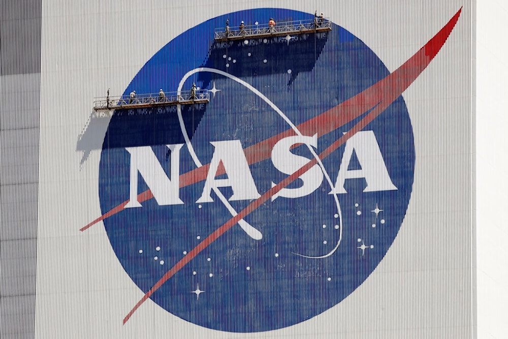 Workers on scaffolding repaint the NASA logo near the top of the Vehicle Assembly Building at the Kennedy Space Center in Cape Canaveral, Fla., Wednesday, May 20, 2020. (AP)