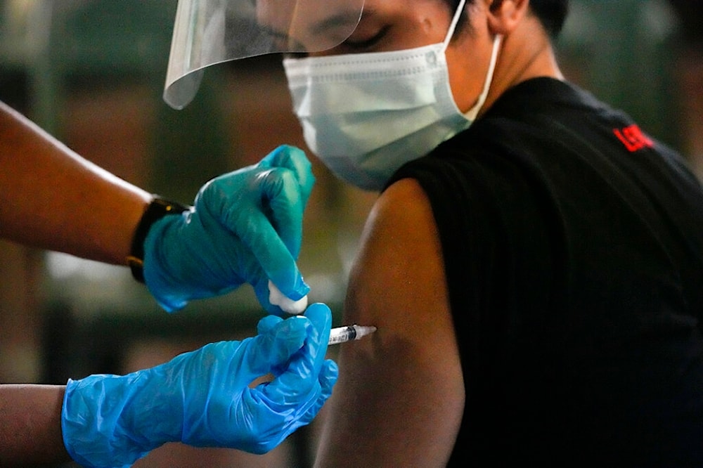 A man is inoculated with Pfizer COVID-19 vaccine during a nationwide vaccination drive at a school in Navotas, Philippines on Wednesday, Dec. 1, 2021. (AP) 