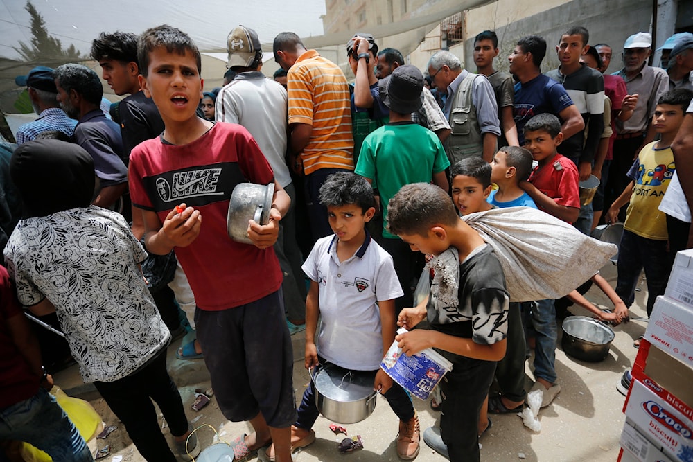 Palestinian children are waiting in line to receive food. (@UNRWA)