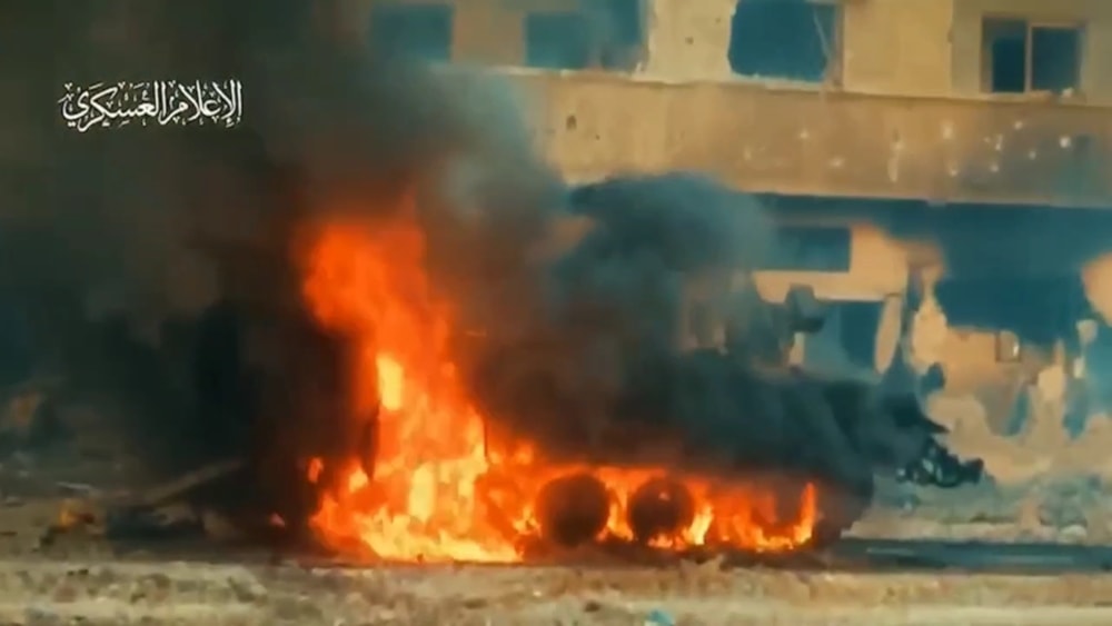 An Israeli armored personnel carrier is seen up in flames after al-Qassem Brigades elite forces in al-Shujaiya in a video published by the Resistance on December 6, 2023. (Al-Qassam Brigades/ Military Media)