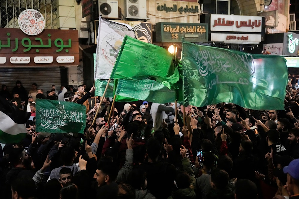 Palestinians wave Hamas flags as they celebrate the Israeli release of Palestinian prisoners in the West Bank city of Nablus, November 24, 2023 (AP)