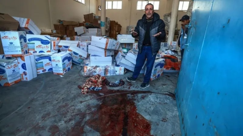 A Palestinian man  gestures near a pool of blood at an UNRWA warehouse and distribution center in Rafah, in the southern Gaza Strip, following an Israeli strike on March 13, 2024. (AFP)