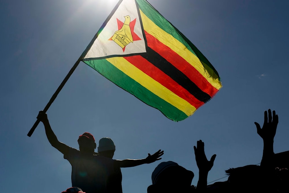 A man is seen raising the national flag of Zimbabwe during a political rally  in Bulawayo, Zimbabwe, Saturday July 21, 2018. (AP)