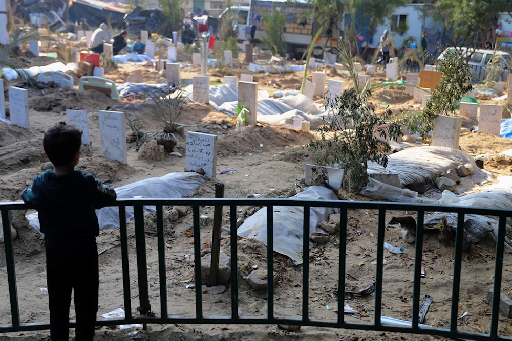  A Palestinian child looks at the graves of people killed in the Israeli bombardment of the Gaza Strip and buried inside the Shifa Hospital grounds in Gaza City, Sunday, Dec. 31, 2023. (AP)