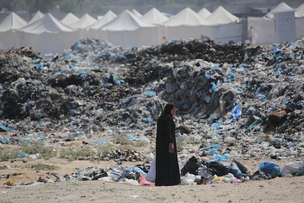 A woman salvaging items from a growing waste dump along a tent displacement camp west of Nuseirat, in central Gaza in May 2024. (AFP)