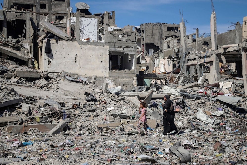 A Palestinian woman and girl walk through rubbles of destroyed homes in northern Gaza, Friday, May 31, 2024. (AP Photo/Enas Rami)