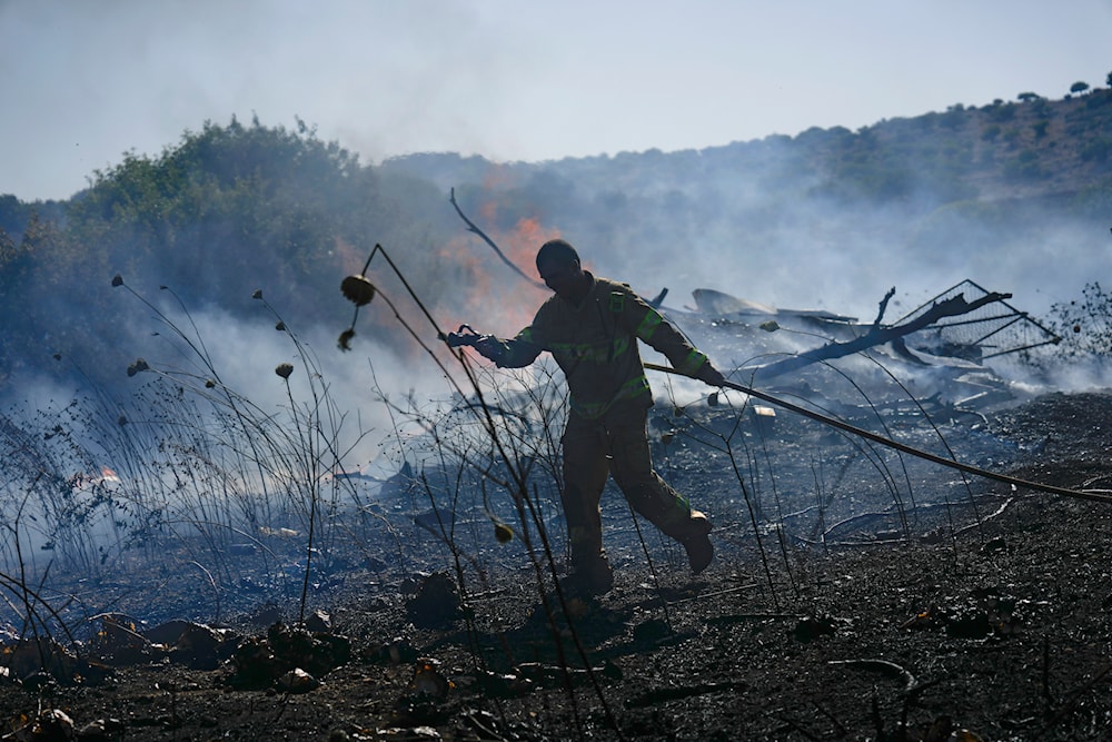 An Israeli firefighter works to extinguish a fire burning in an area near the community of Ramot Naftali, by the border with Lebanon, northern occupied Palestine, June 4, 2024 (AP)