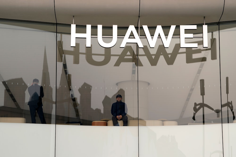 A visitor to store looks out near a logo for Chinese telecoms equipment giant Huawei in Beijing, Tuesday, March 26, 2024. (AP)