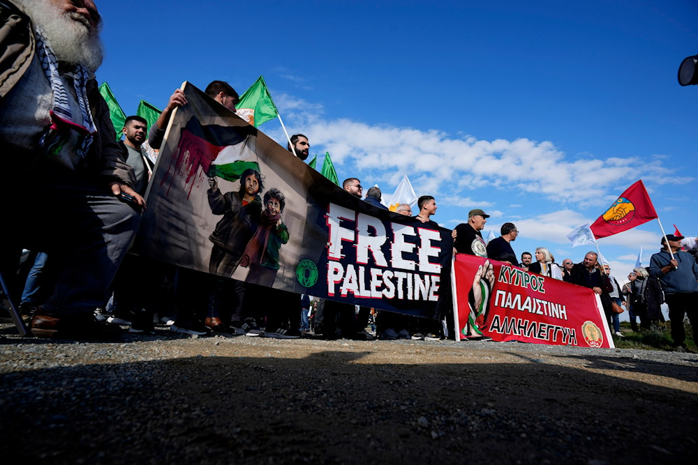 Demonstrators hold banners, condemning the Israeli occupation's genocide in Gaza outside the entrance of RAF Akrotiri, near the southern port city of Limassol, Cyprus, January 14, 2024 (AP)