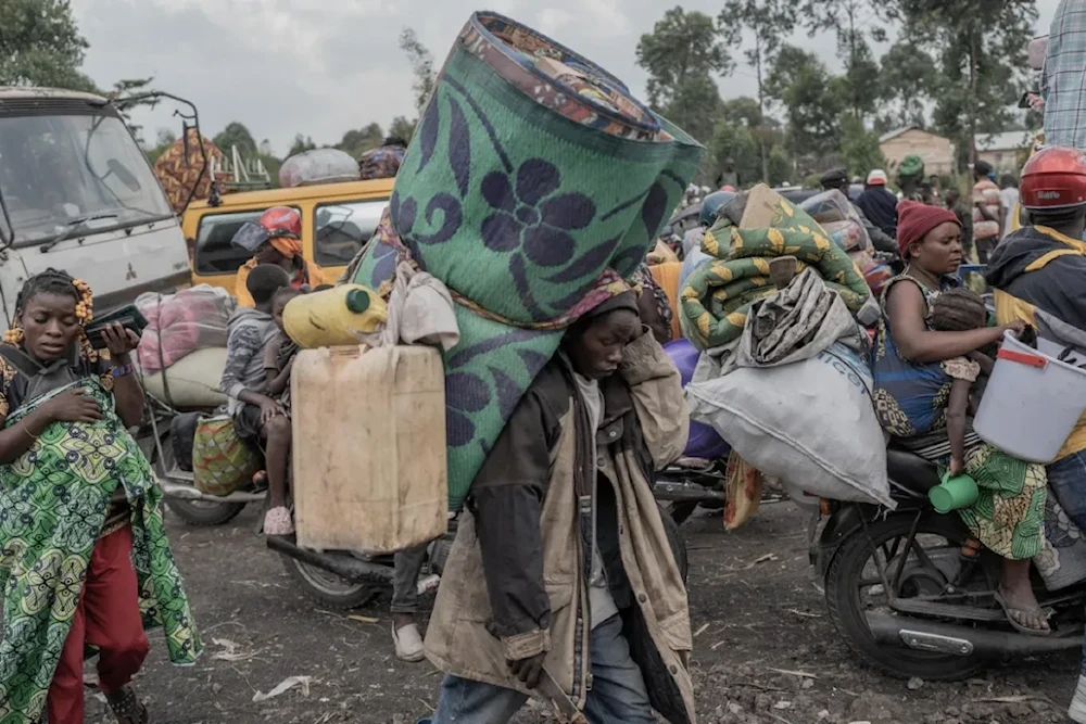 People carry their belongings as they flee eastern DR Congo's Masisi territory (AFP)