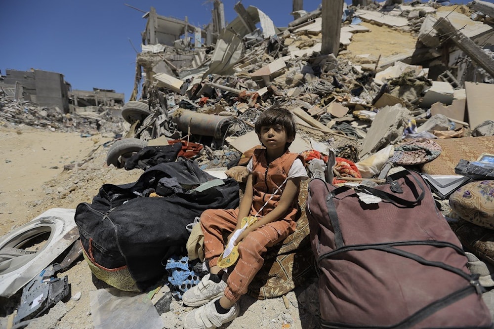 A Palestinian child sits amid rubble of a residential building bombed by IOF in Gaza on June 2, 2024. (UNRWA)