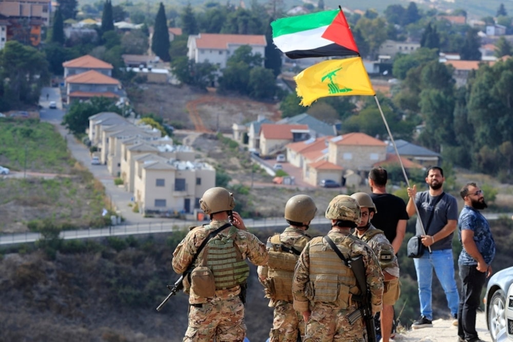 Lebanese soldiers stand at a hill that overlooks the Israeli settlement of Metula, as a man waves the Palestinian and Hezbollah flags, Lebanon, OCT 9, 2023. (AP)