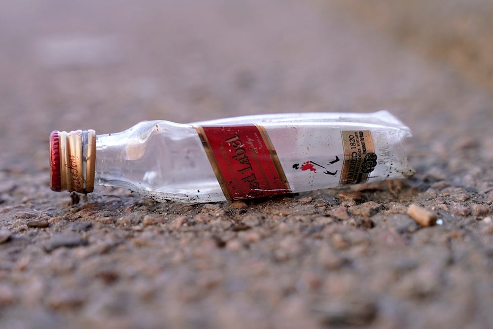 An empty miniature bottle that once contained liquor rests on a street near a sidewalk, Monday, April 3, 2023, in Boston. (AP)