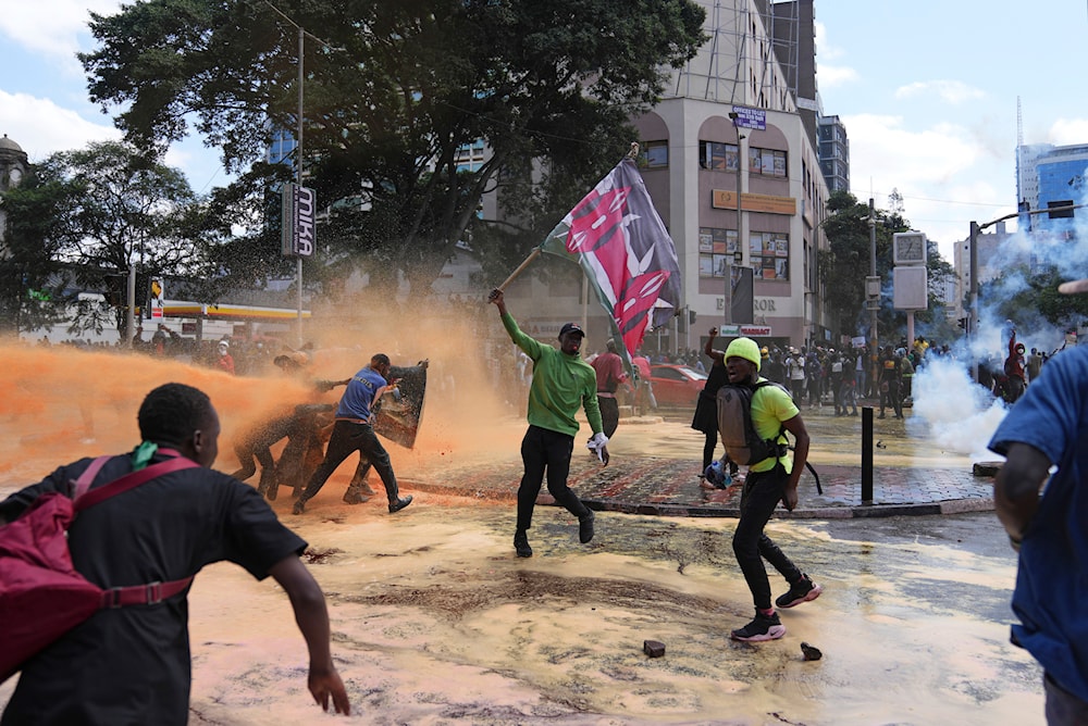 Protesters scatter as Kenya police spray a water canon at them during a protest over proposed tax hikes in a fina