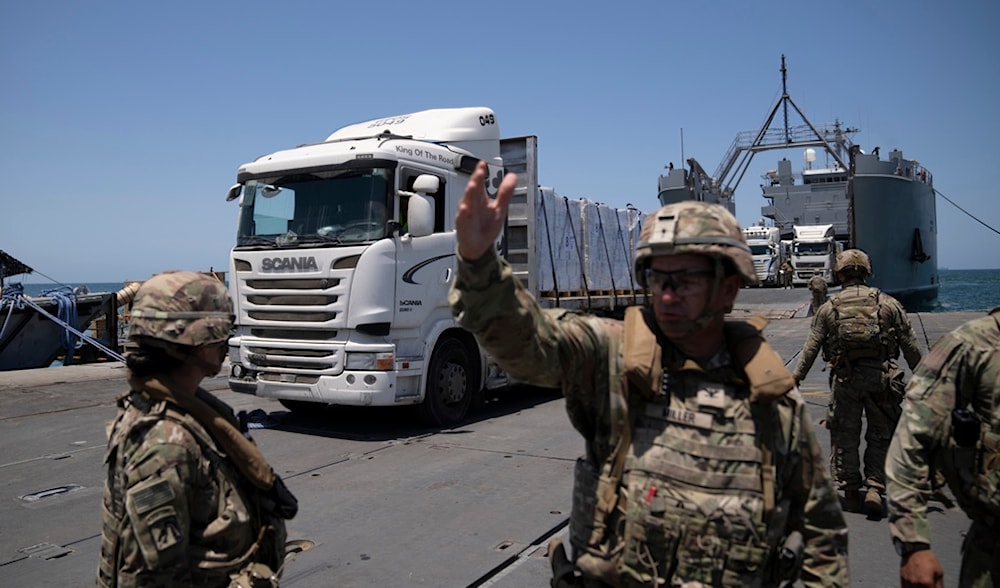 A U.S. Army soldier gestures as trucks loaded with humanitarian aid arrive at the U.S.-built floating pier Trident before reaching the beach on the coast of the Gaza Strip, Tuesday, June 25, 2024. (AP)