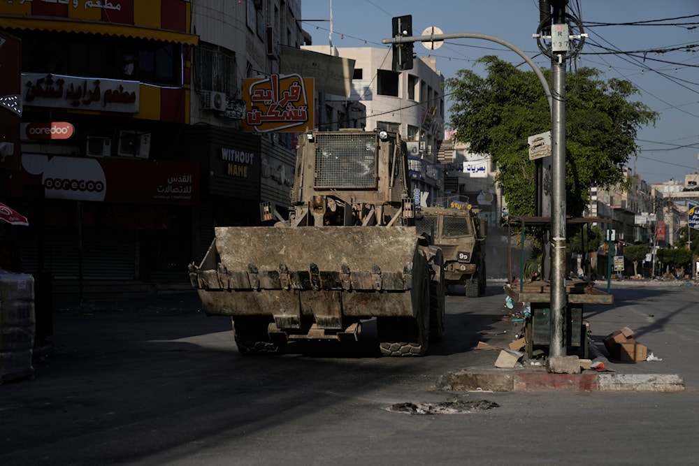 An Israeli bulldozer and an armoured vehicle move on a street during a raid in the occupied West Bank city of Jenin, occupied Palestine, June 6, 2024 (AP)