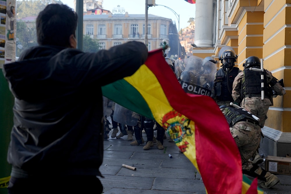 A supporter of President Luis Arce waves a Bolivian flag as soldiers flee from Plaza Murillo, after a failed coup attempt, in La Paz, Bolivia, Wednesday, June 26, 2024. (AP)