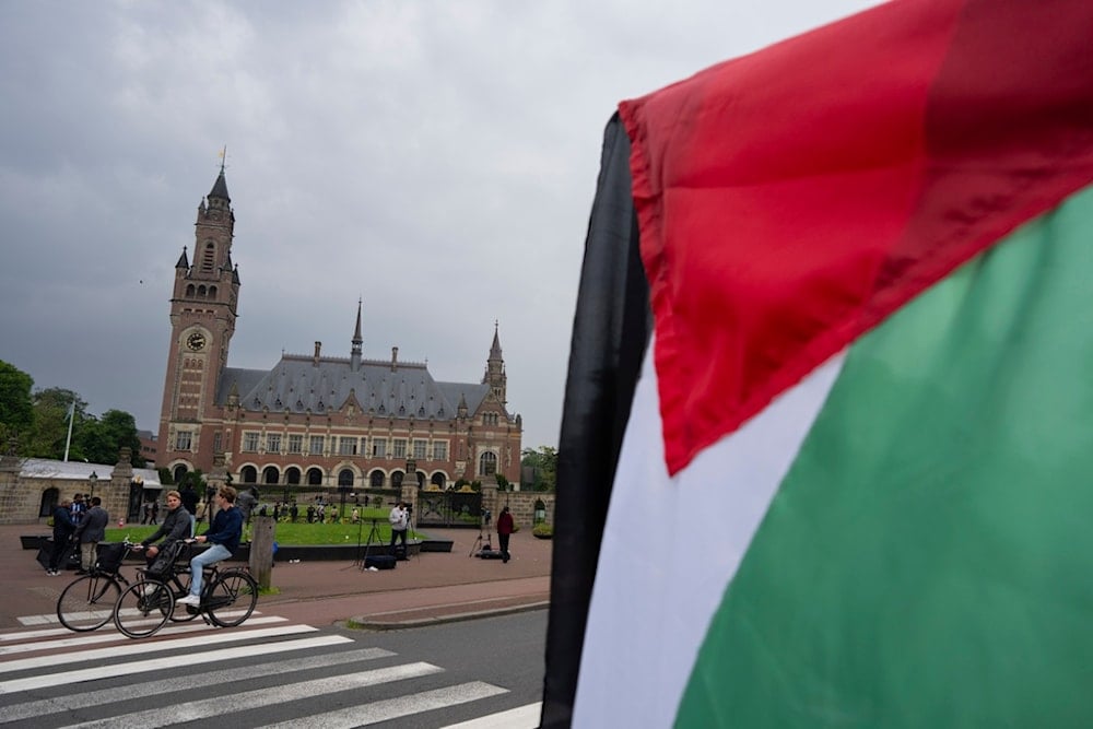 A  demonstrator waves the Palestinian flag outside the Peace Palace, rear, housing the International Court of Justice, or World Court, in The Hague, Netherlands, Friday, May 24, 2024.