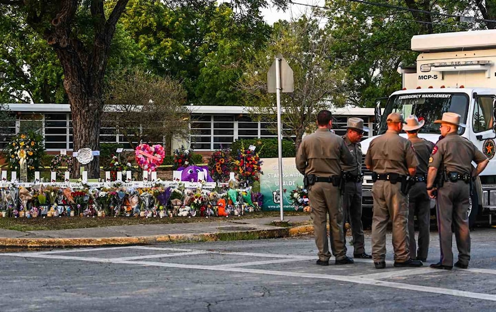 Police officers speak near a makeshift memorial for the shooting victims outside Robb Elementary School in Uvalde, Texas, May 27, 2022. (AFP via Getty Images)