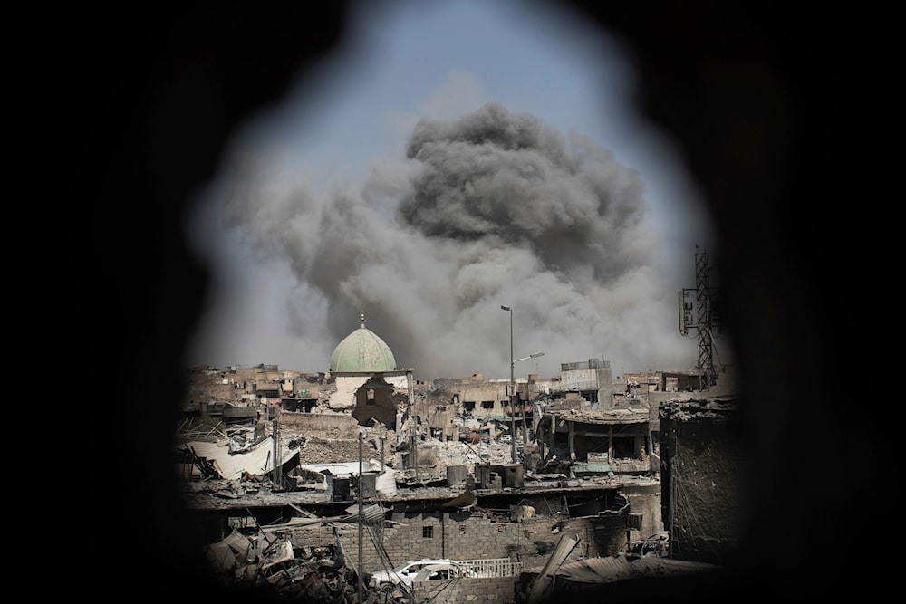 A bomb explodes behind the al-Nuri mosque complex, as seen through a hole in the wall of a house, in Mosul, Iraq, June 29, 2017. (AP)