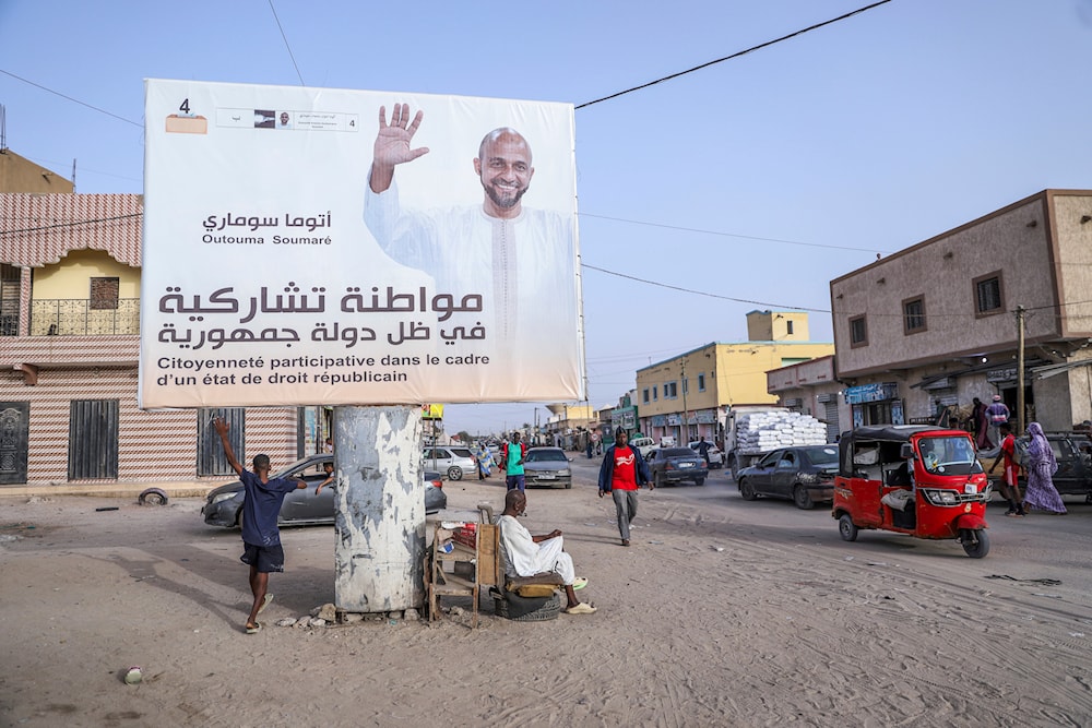 People rest under an electoral banner for presidential candidate Outouma Soumaré ahead of the presidential candidate, in Nouakchott, Mauritania, on June 25, 2024. (AP)