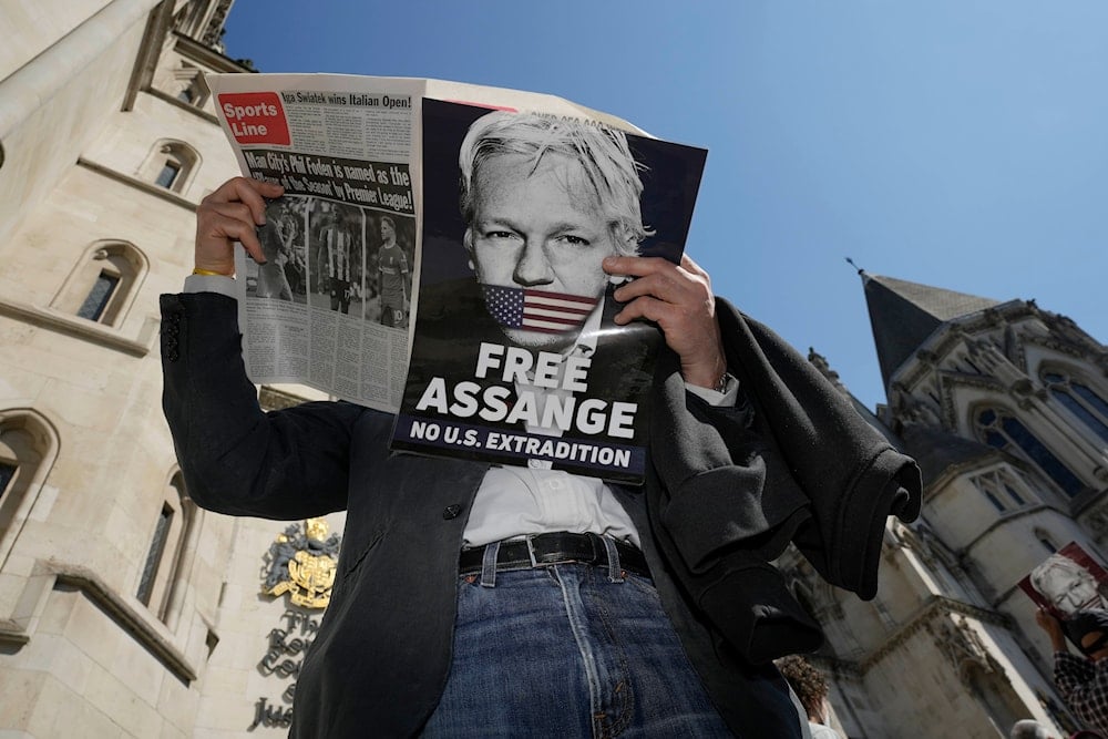 A protester reads a newspaper outside the High Court in London, Monday, May 20, 2024. (AP)