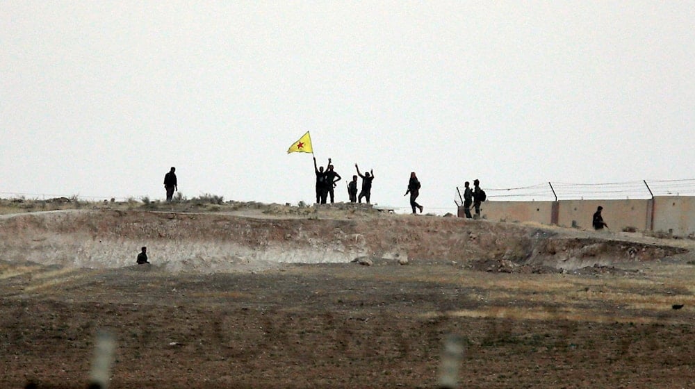 Kurdish fighters with the Kurdish People's Protection Units, or YPG, wave their yellow triangular flag and wave their arms in the outskirts of Tal Abyad, Syria, June 15, 2015 (AP)