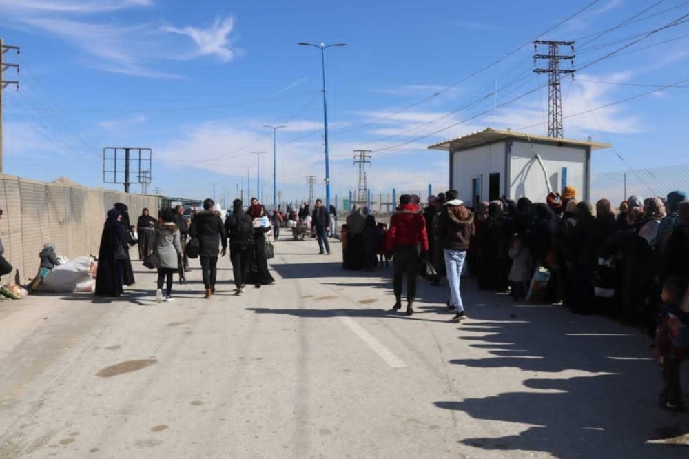 Syrians wait their turn to cross between areas controlled by the Syrian government and the Kurdish 