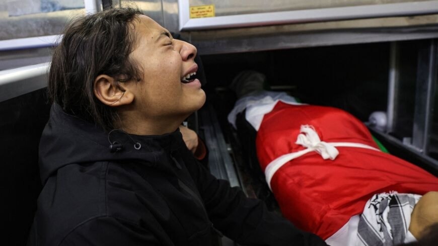 A child mourns over the body of one of five people killed in the occupied West Bank city of Jenin during an overnight Israeli incursion, at the morgue of a hospital on November 26, 2023. (AFP via Getty Images)