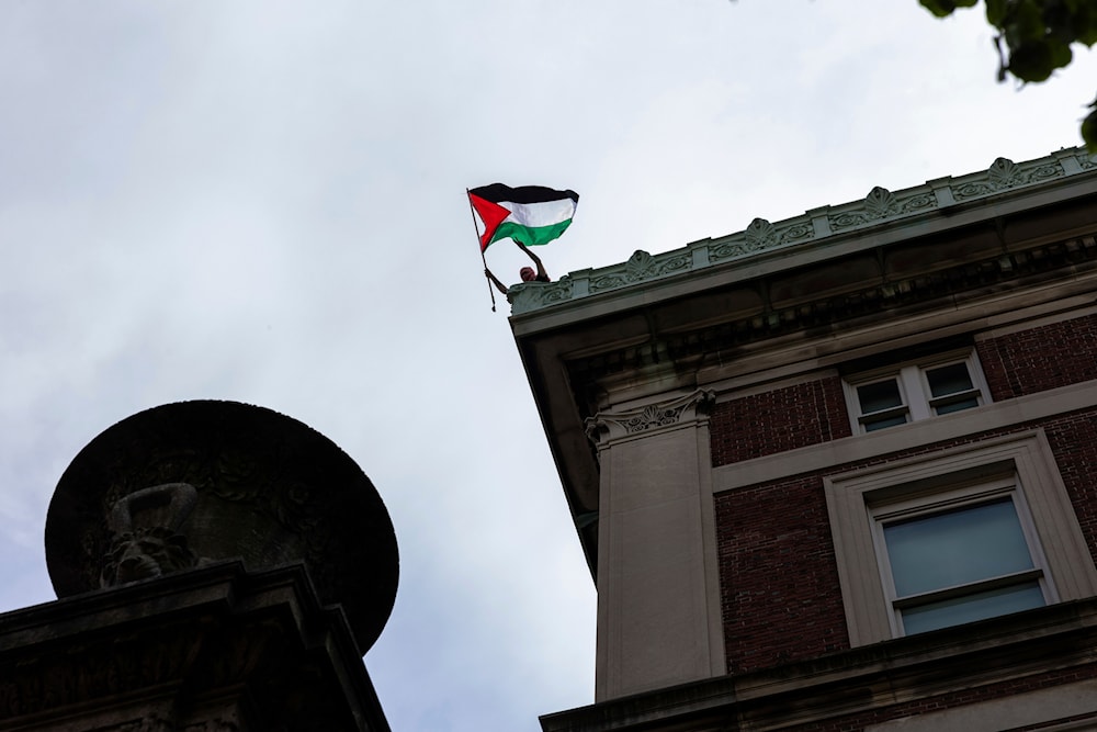 A pro-Palestinian protestor occupying Hamilton Hall waves a Palestinian flag on the roof of the building at Columbia University, on April 30, 2024 in New York. (AP)