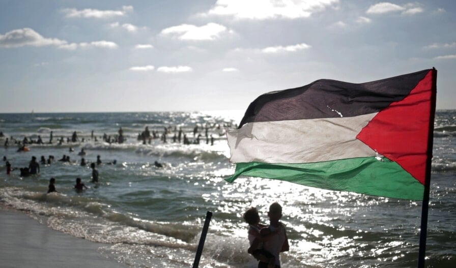 In this Monday, June 23, 2014 photo, a Palestinian flag waves as people enjoy a summer day at the beach of Gaza City, the besieged Gaza Strip, Palestine.(AP)