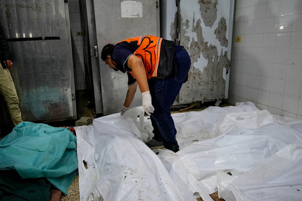 A Palestinian medic checks the covered body of Iyadd al-maghari, the mayor of Nusseirat refugee camp, killed in the Israeli bombardment of the Gaza Strip, at the morgue of al-Aqsa Martyrs hospital in Deir al-Balah, central Gaza Strip, on June 6, 2024. (AP)