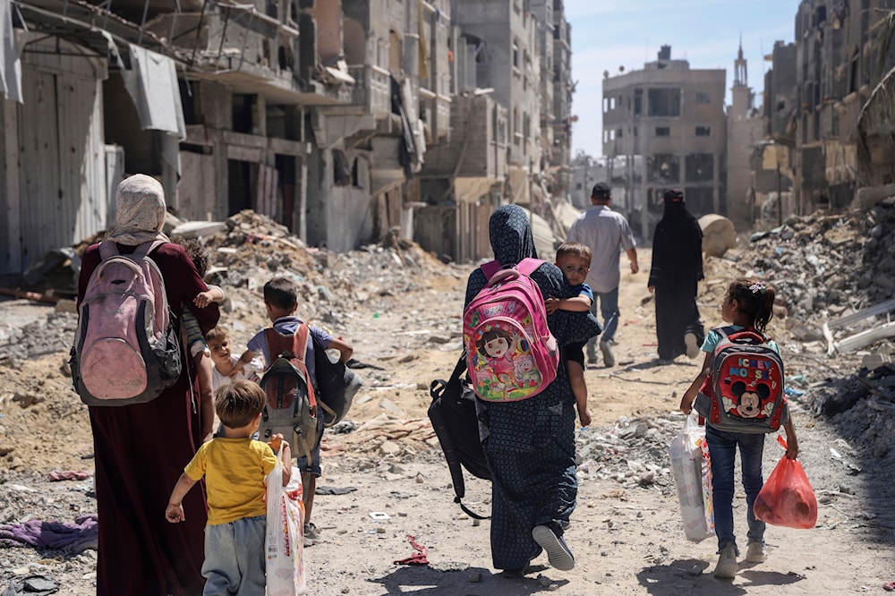 Palestinian women and their children walk though destruction in the wake of an Israeli air and ground offensive in Jabalia, northern Gaza Strip after the Israeli occupation forces withdrew from the area, May 31, 2024 (AP)