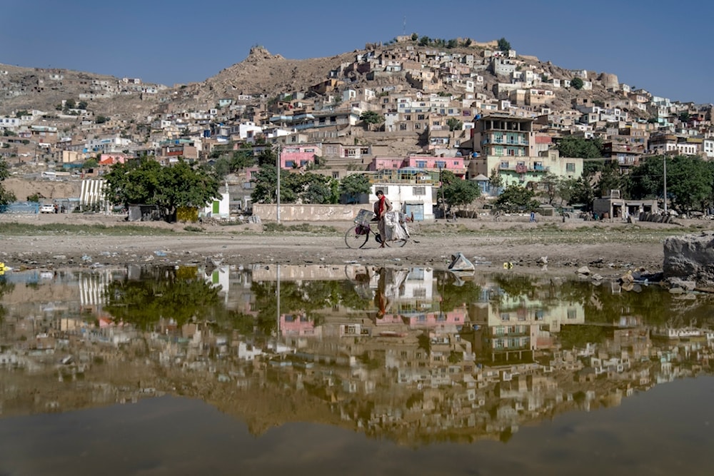 An Afghan traveling salesman poses for a portrait with his bicycle on the outskirts of Kabul, in Afghanistan, Wednesday, June 14, 2023 (AP Photo/Ebrahim Noroozi)