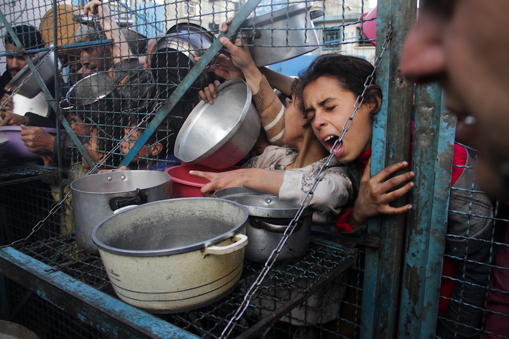 Palestinians line up to receive meals at Jabaliya refugee camp in the Gaza Strip, occupied Palestine, March 18, 2024 (AP)