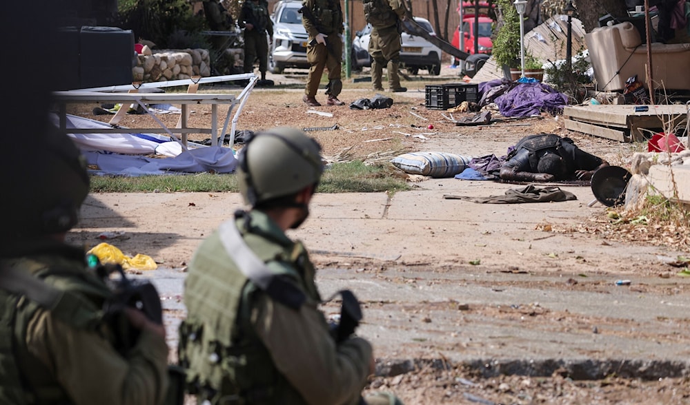 Israeli soldiers stand near the body of a Palestinian terrorist in Kibbutz Kfar Aza near the Gaza Strip, on October 10, 2023. (AFP)