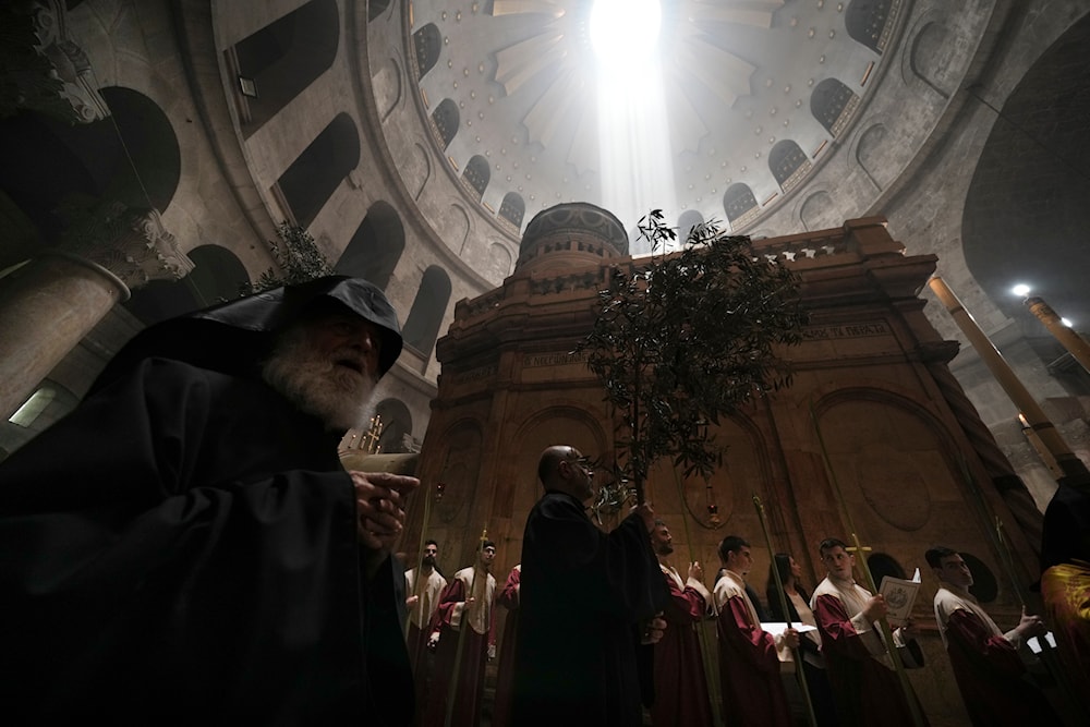 Orthodox Christian clergy marks Palm Sunday at the Church of the Holy Sepulchre, a place where Christians believe Jesus Christ was crucified, buried and resurrected, in al-Quds, on April 17, 2022. (AP)