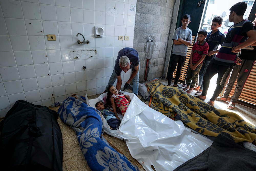 Palestinians check the bodies of their relatives killed in the Israeli bombardment of the Gaza Strip, at a hospital morgue in Deir al-Balah, on July 13, 2024. (AP)