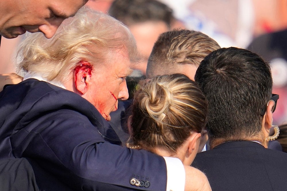 Republican presidential candidate former President Donald Trump is surrounded by U.S. Secret Service agents as he is helped off the stage at a campaign rally in Butler, Pa., Saturday, July 13, 2024. (AP)