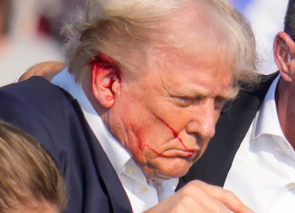 Republican presidential candidate Donald Trump is surrounded by Secret Service agents as he is helped off the stage. (AP)