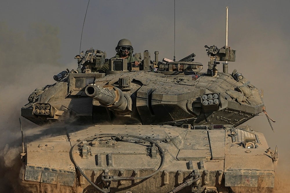 An Israeli soldier moves on the top of a tank near the separation line with Gaza, as seen from southern occupied Palestine, Sunday, July 14, 2024. (AP Photo/Tsafrir Abayov)