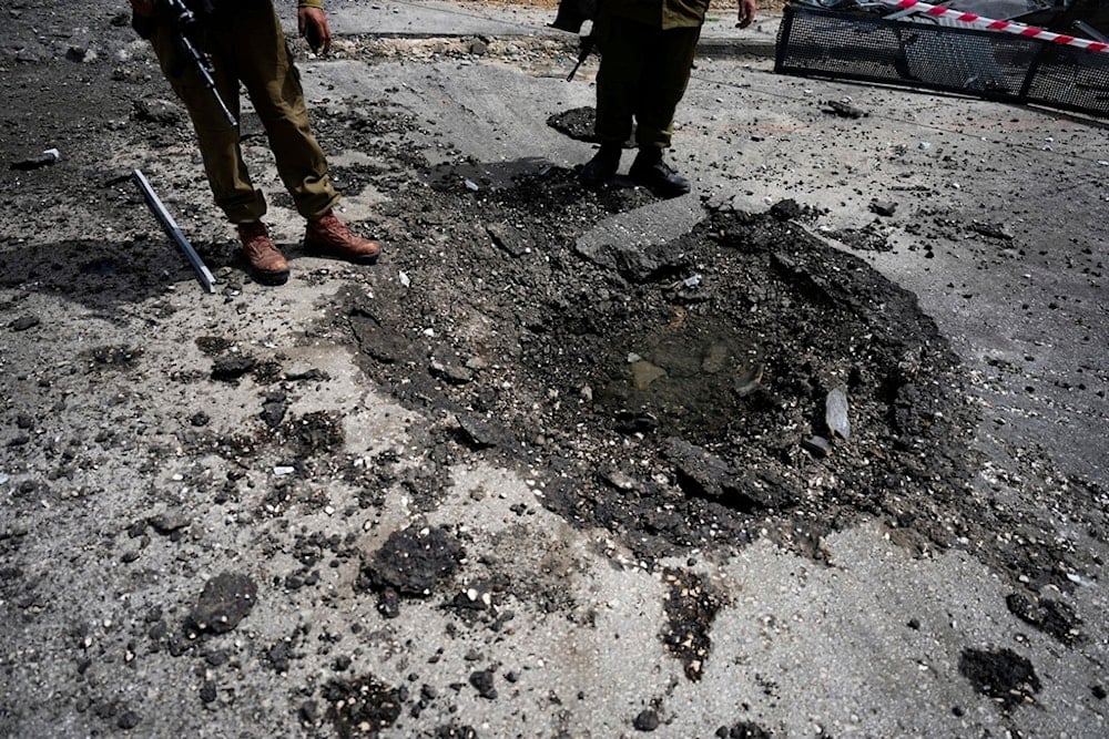 Israeli security forces examine the site hit by a rocket fired from Lebanon, in Kiryat Shmona, northern occupied Palestine, Wednesday, March 27, 2024. (AP)