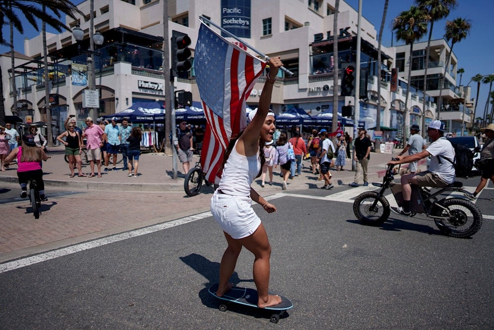 A woman rides a skateboard at a rally in support of Republican presidential candidate former President Donald Trump in Huntington Beach, Calif., Sunday, July 14, 2024. (AP)