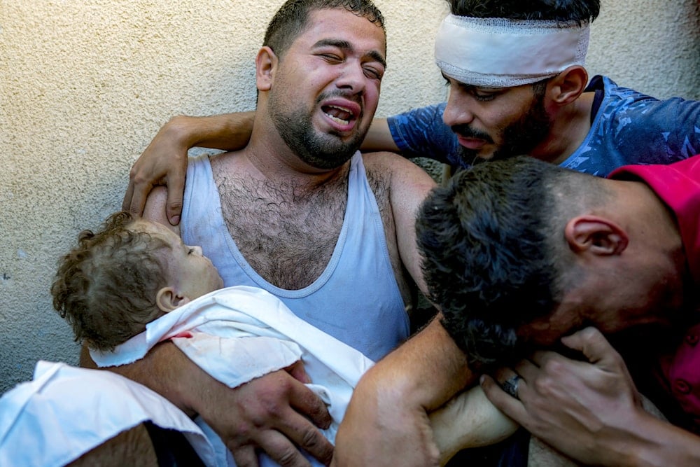 Palestinian Mahmoud Mikdad morns as holding the body of his 21-month-old child Yaman, killed in the Israeli bombardment of the Gaza Strip, at a hospital morgue in Deir al-Balah, on July 16, 2024. (AP)