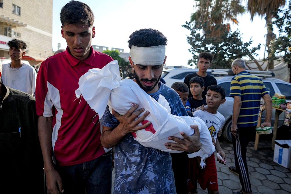 A relative holds the body of a child killed in the Israeli bombardment of the Gaza Strip, at a hospital morgue in Deir al-Balah, Tuesday, July 16, 2024. (AP)