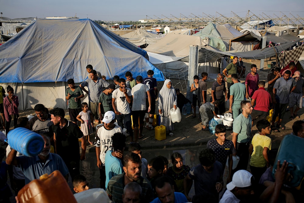 Palestinians displaced by the Israeli bombardment of the Gaza Strip queue for water at a makeshift tent camp in the southern town of Khan Younis, Monday, July 1, 2024. (AP)