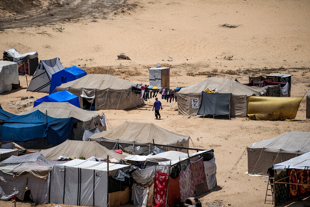 A Palestinian man displaced by the Israeli bombardment of the Gaza Strip, walks at a makeshift tent camp in Khan Younis, southern Gaza Strip, July 4, 2024 (AP)