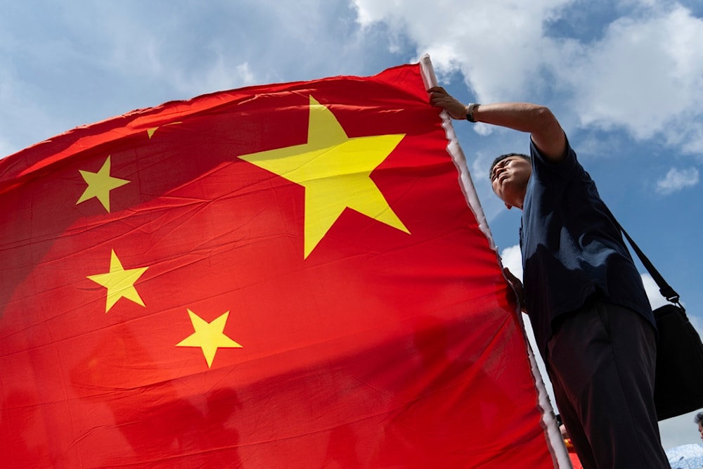 A pro-Beijing supporter holds Chinese flag to mark the 27th anniversary of Hong Kong's return to Chinese rule in Hong Kong, Monday, July 1, 2024. (AP Photo/Chan Long Hei)